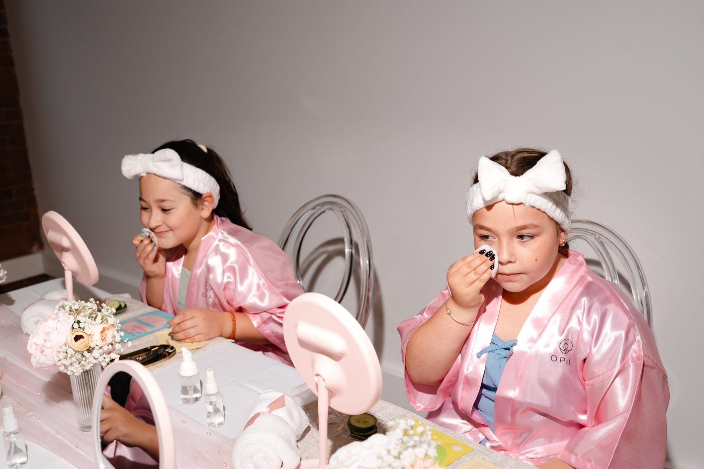 Two girls smiling while doing a face mask activity together at a kids spa birthday party