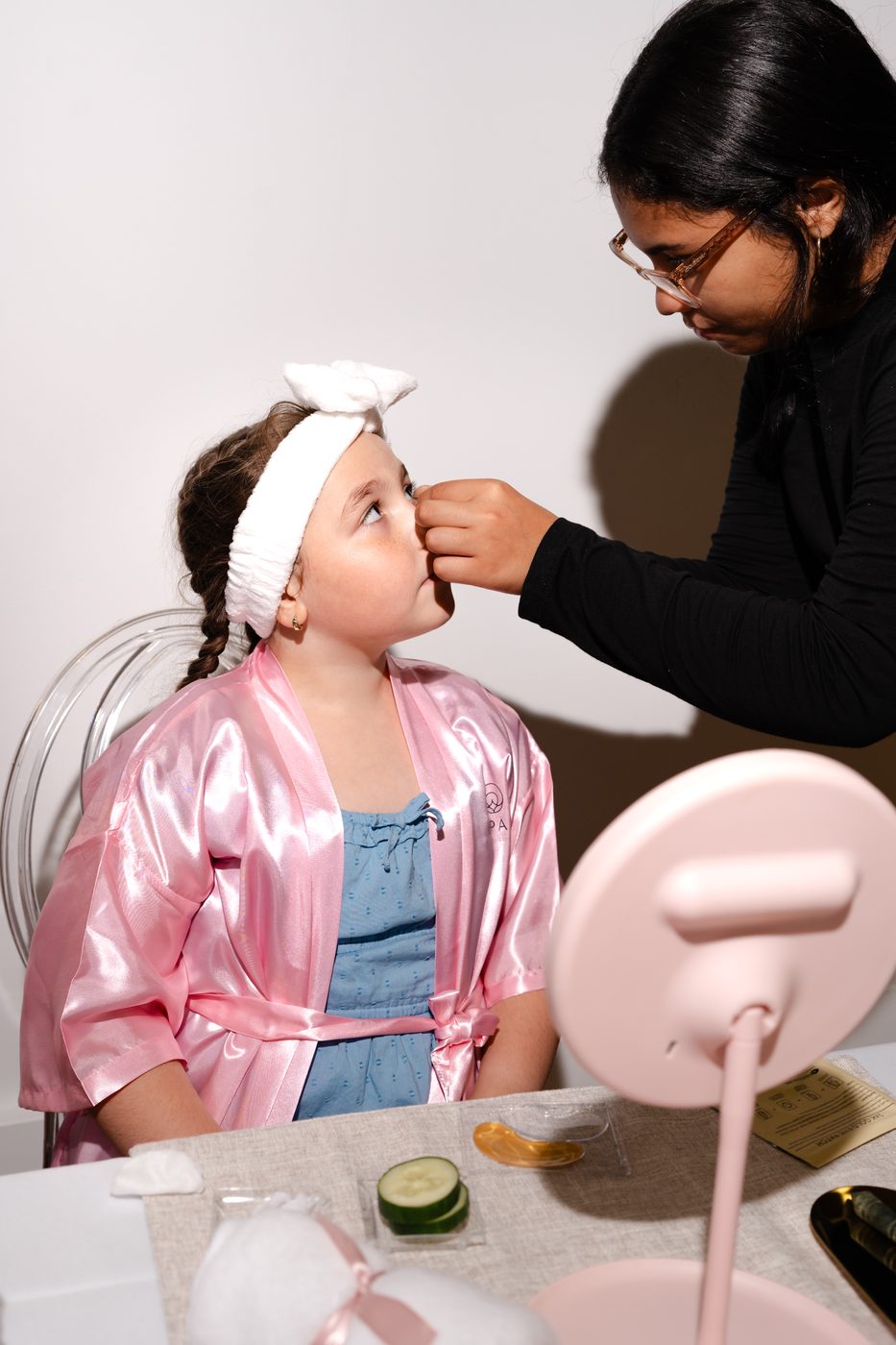 Opal Beauty Events staff member applying a gold eye patch during a kids spa facial