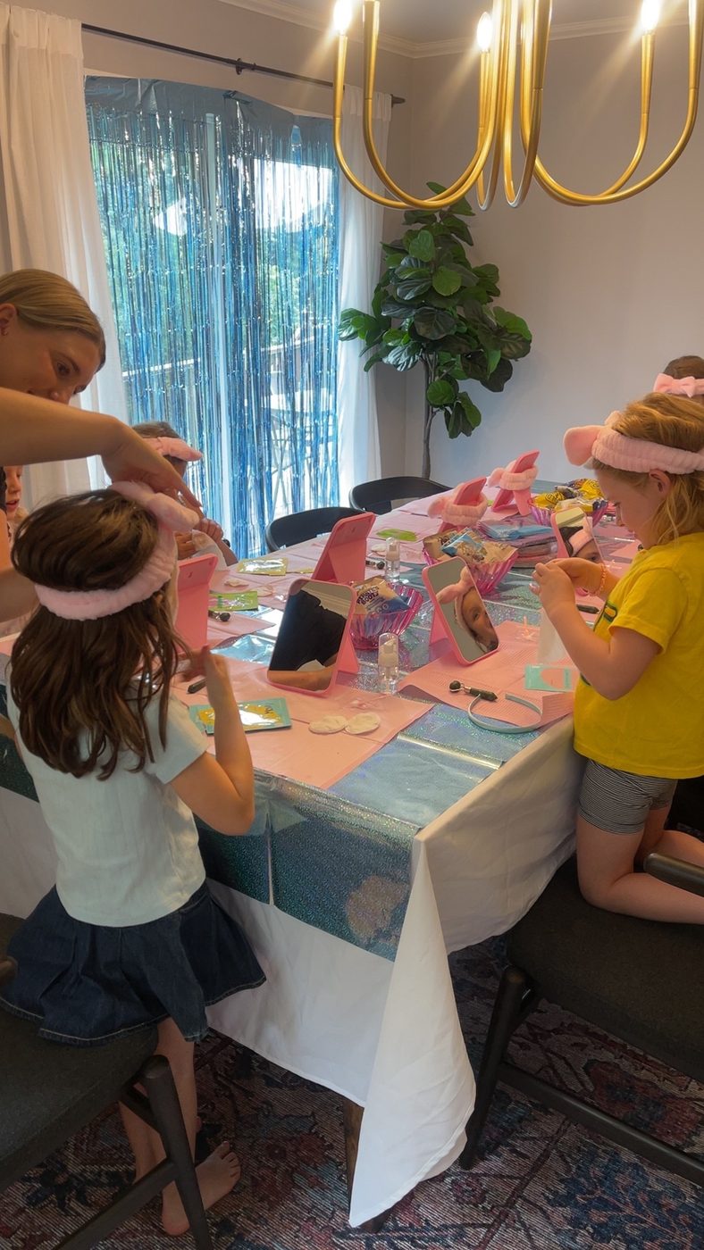 A young guest helping her friend fasten a spa headband before nail painting begins