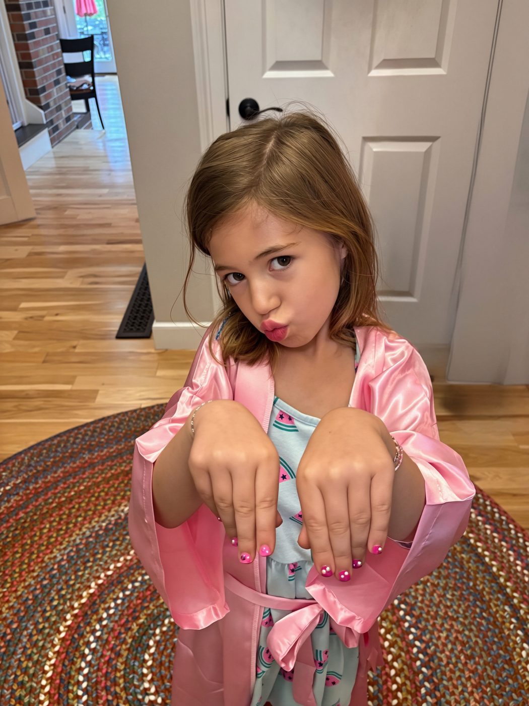 A birthday girl in her pink Opal robe showing off her freshly painted nails with a playful smile
