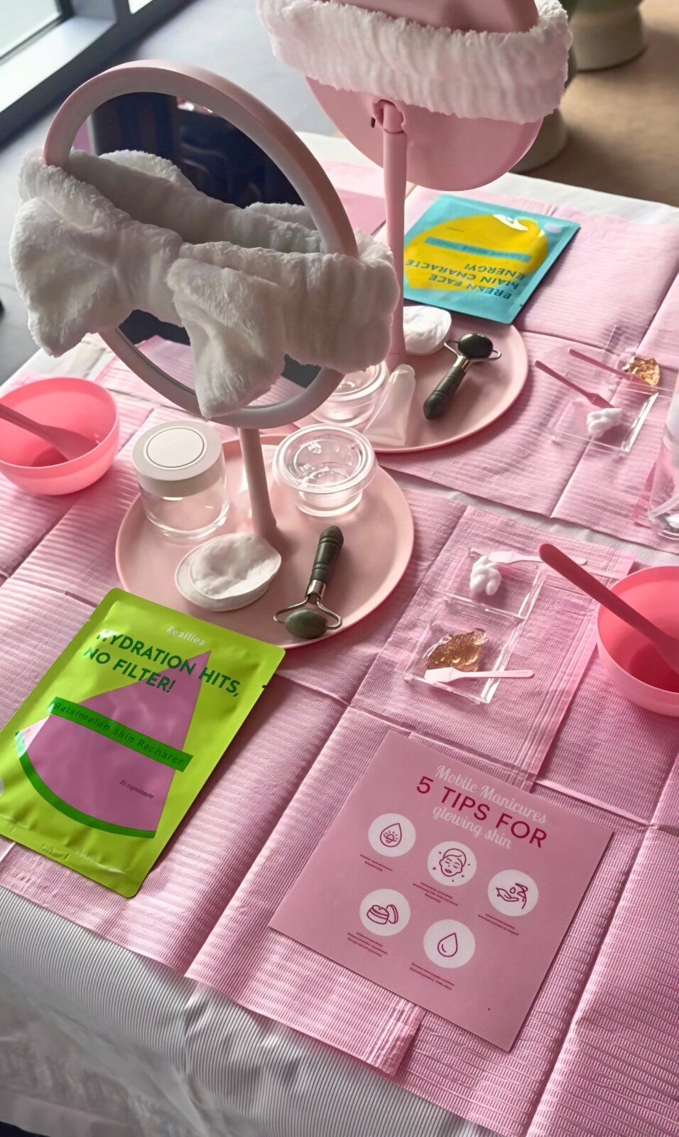 Kids spa party facial station with pink mirrors, bow headbands, face masks and jade rollers
