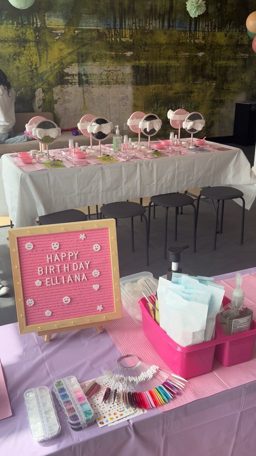 Kids spa party mirror and facial stations set up with skincare supplies and a personalized Happy Birthday Elliana sign